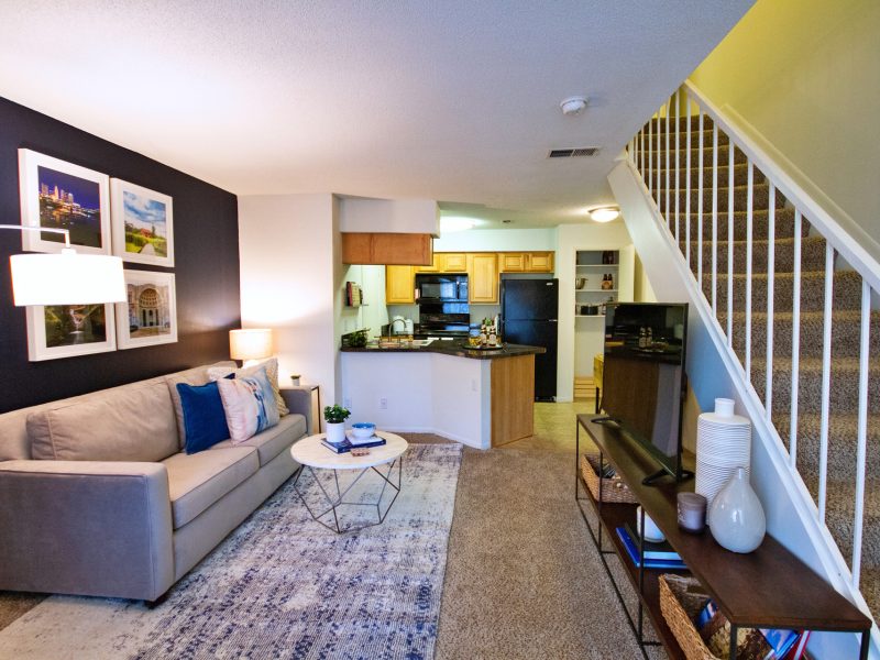 This image shows the premium apartment feature, particularly the living room area featuring a comfy sofa and vibrant wall sceneries. The living area is also featuring a stairway directing through the bedroom area.